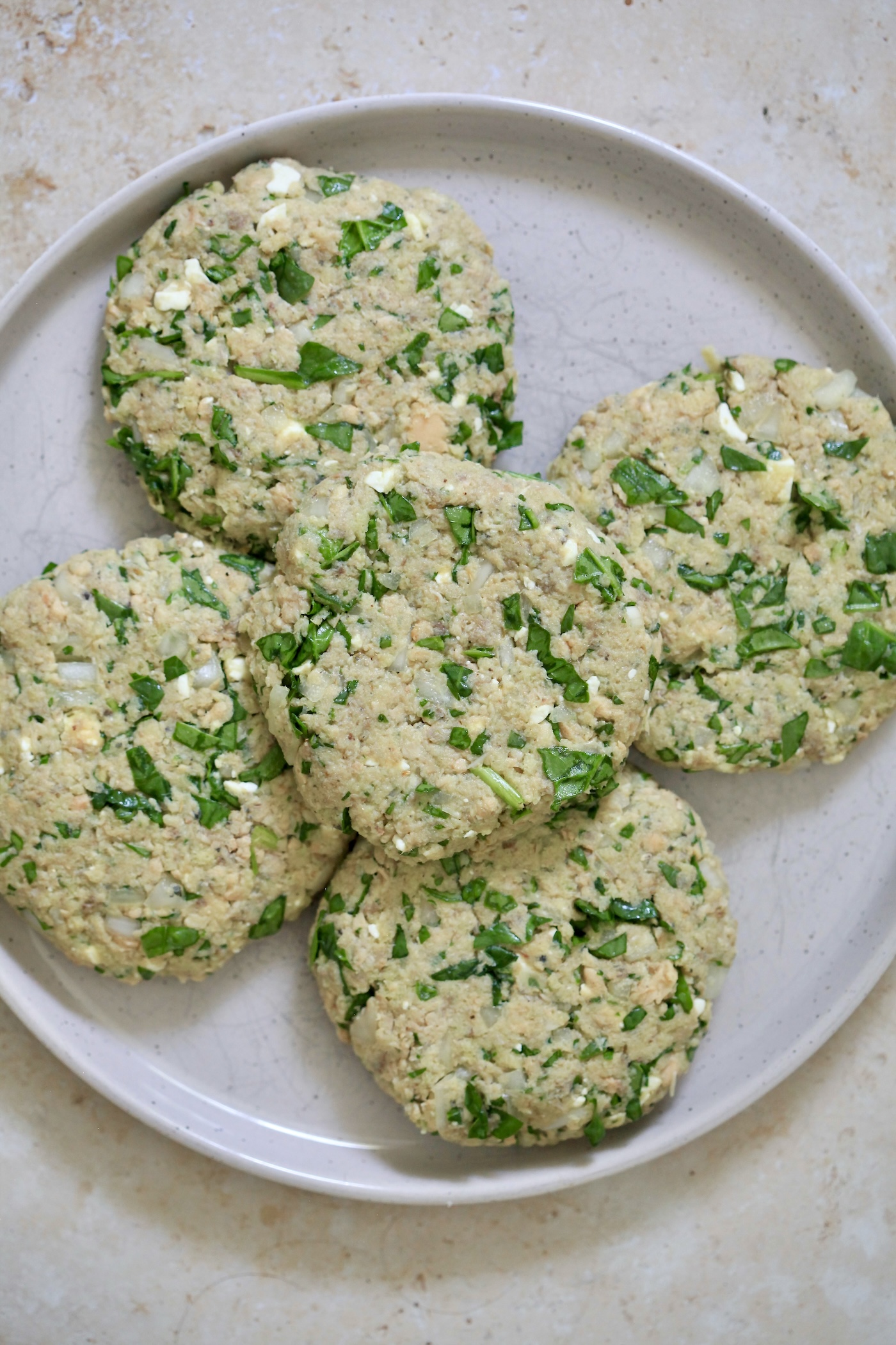 five uncooked salmon spinach burgers on plate