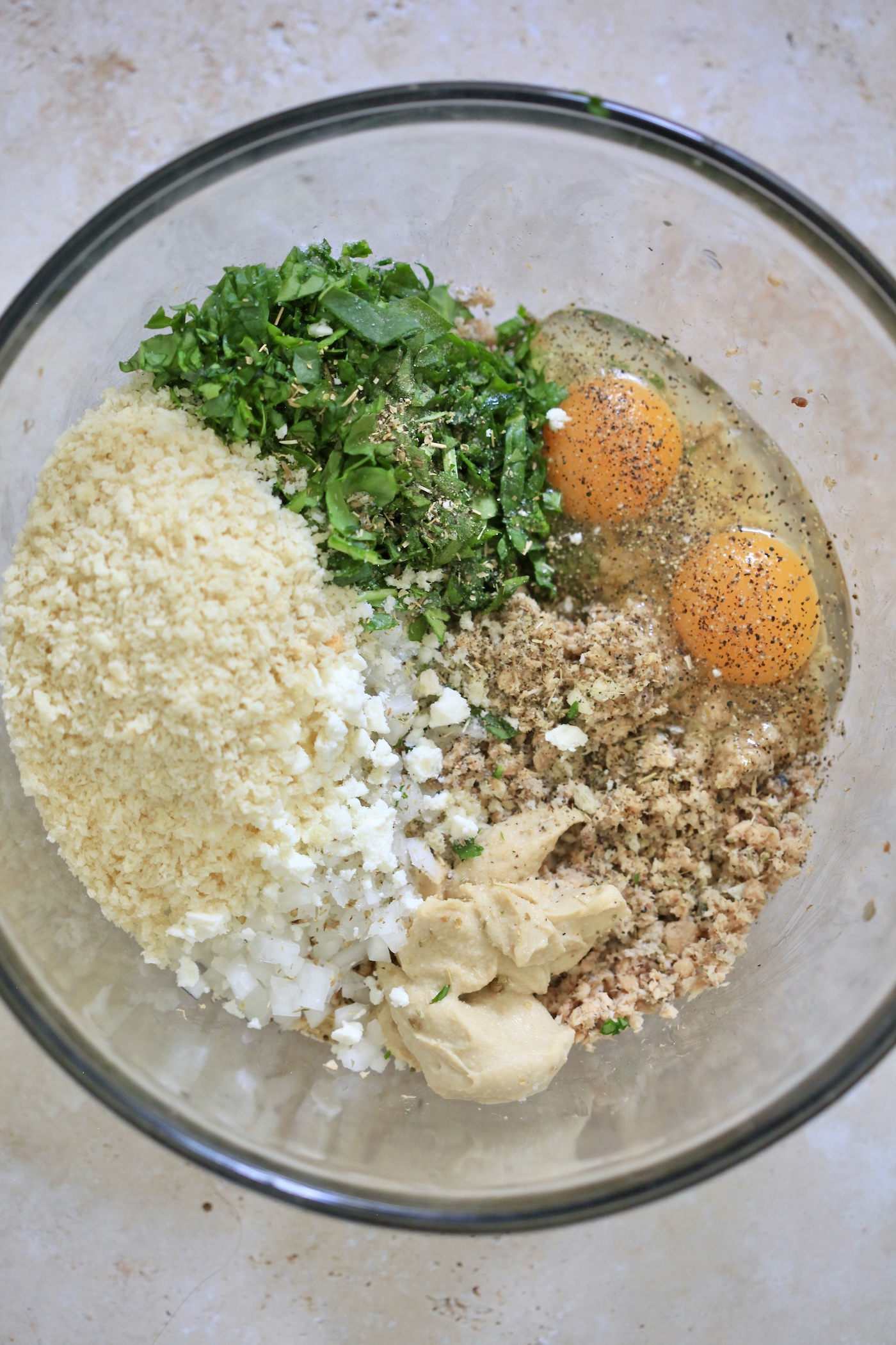 eggs, herbs, and breadcrumbs in bowl with salmon.