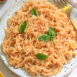 plate of red creamy spaghetti squash on plate with basil.
