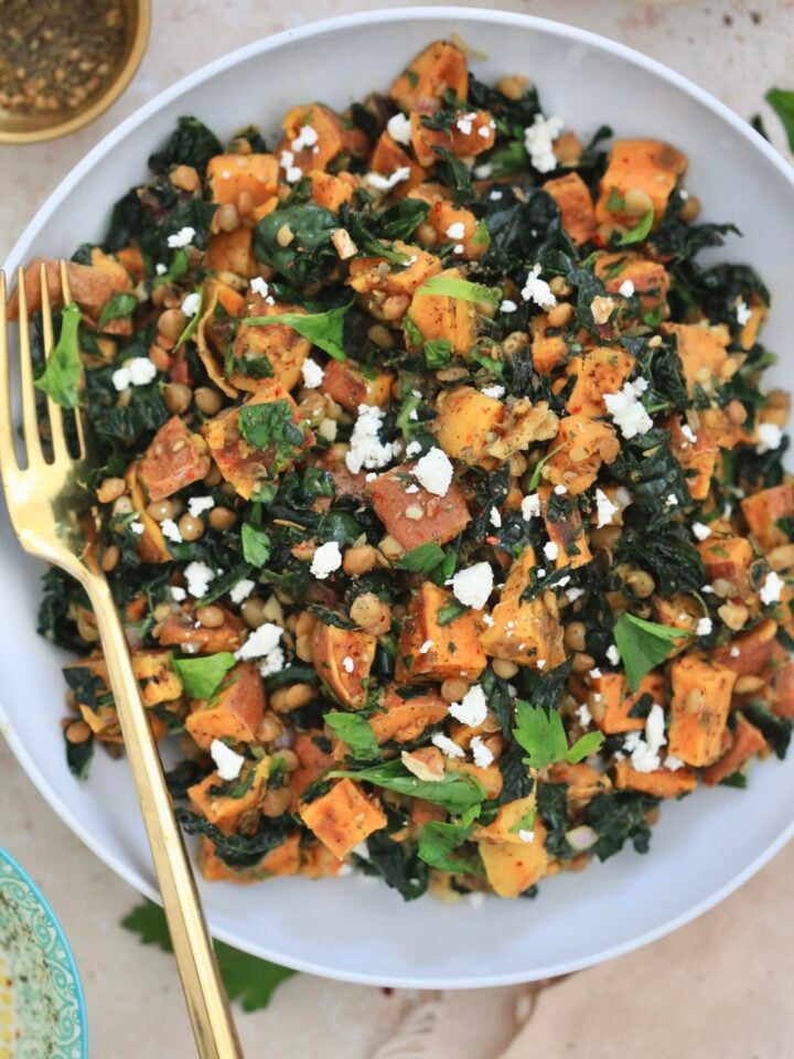 white bowl of salad with sweet potatoes and kale