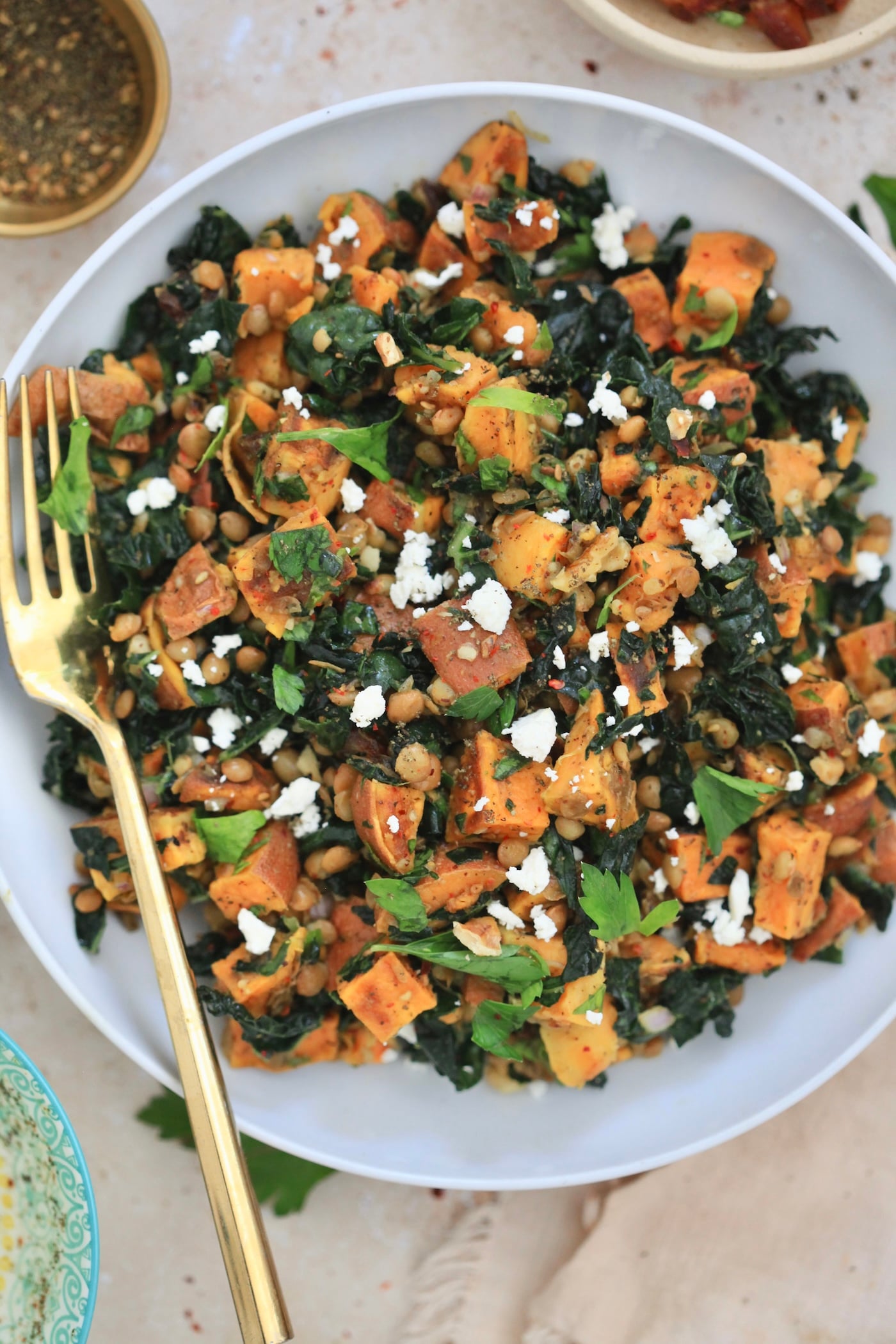 white bowl of salad with sweet potatoes and kale
