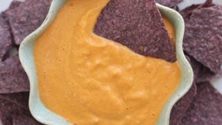 blue bowl of queso dip with corn chips