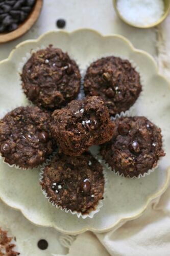 plate of 6 chocolate muffins with bite taken out.
