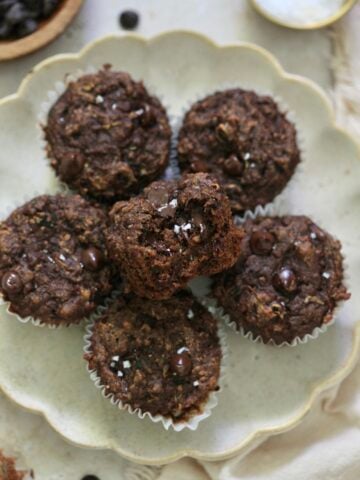 plate of 6 chocolate muffins with bite taken out.