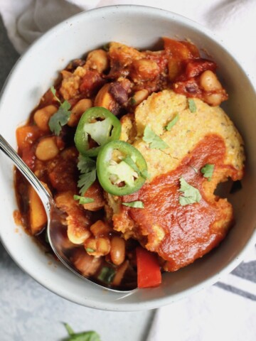 Hearty vegetarian chili topped with cornbread, this cozy Vegan Chili Cornbread Casserole is the perfect meal to feed a crowd! Comfort food at it's finest. Vegan and gluten-free option.