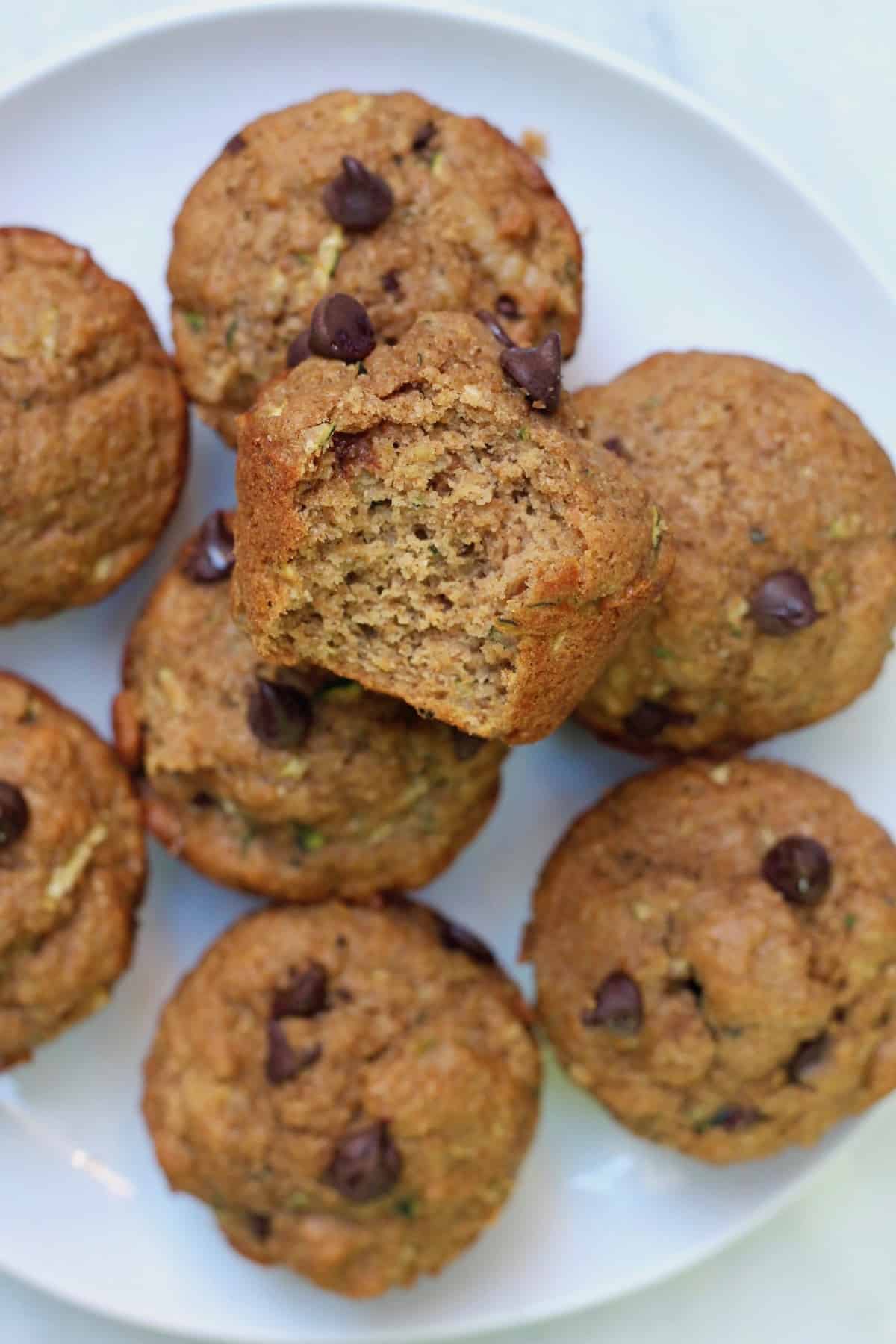 plate of chocolate chip zucchini muffins with bite taken out of it on white