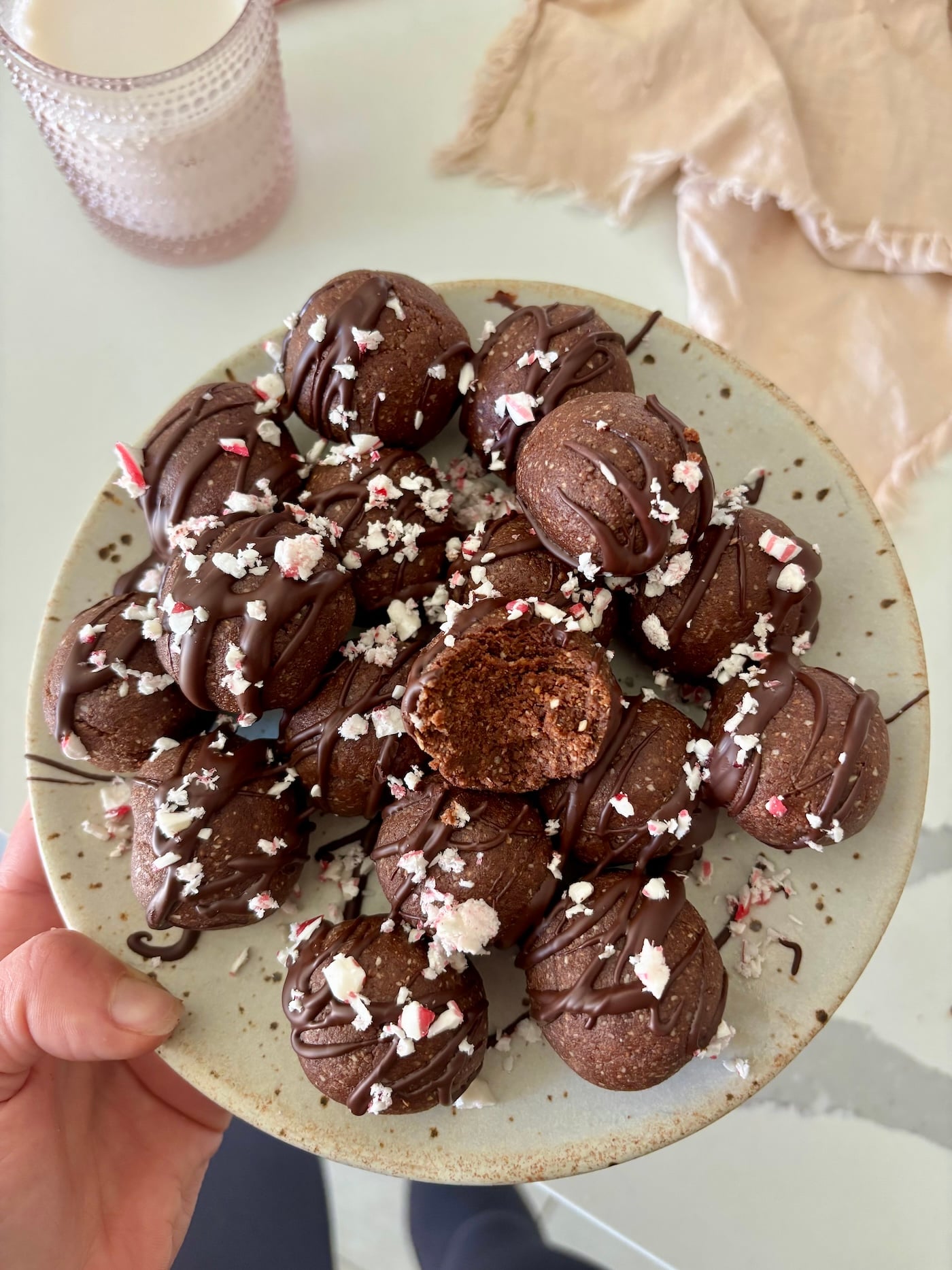 hand holding plate with chocolate balls with candy canes on top.