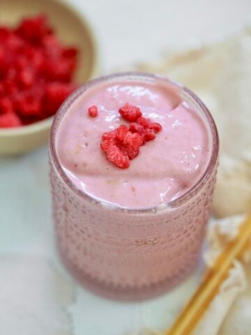 pink smoothie in glass with raspberries.