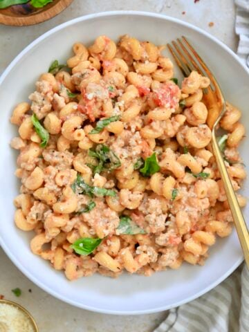bowl of tomato pasta with gold fork.