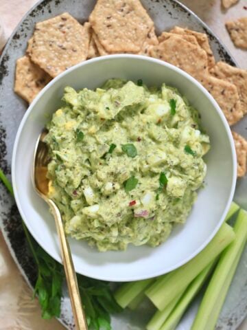 bowl of green egg salad with crackers.