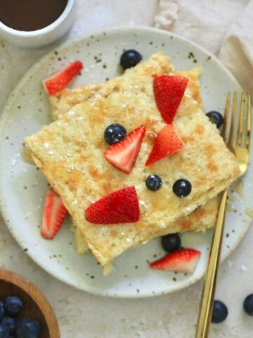 plate with square shaped pancakes and fruit on top.