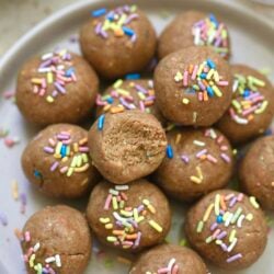 light brown balls on plate with sprinkles and a bite taken out.