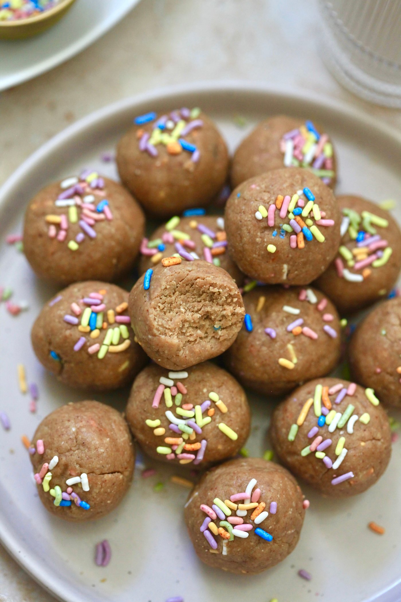 light brown balls on plate with sprinkles and a bite taken out.