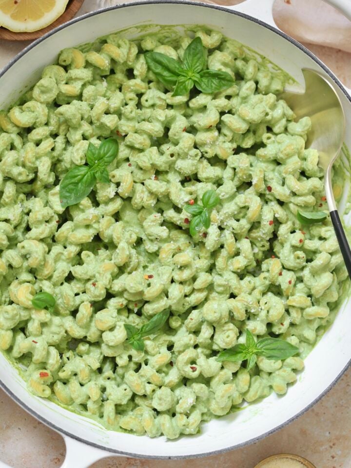 white skillet with green pasta.