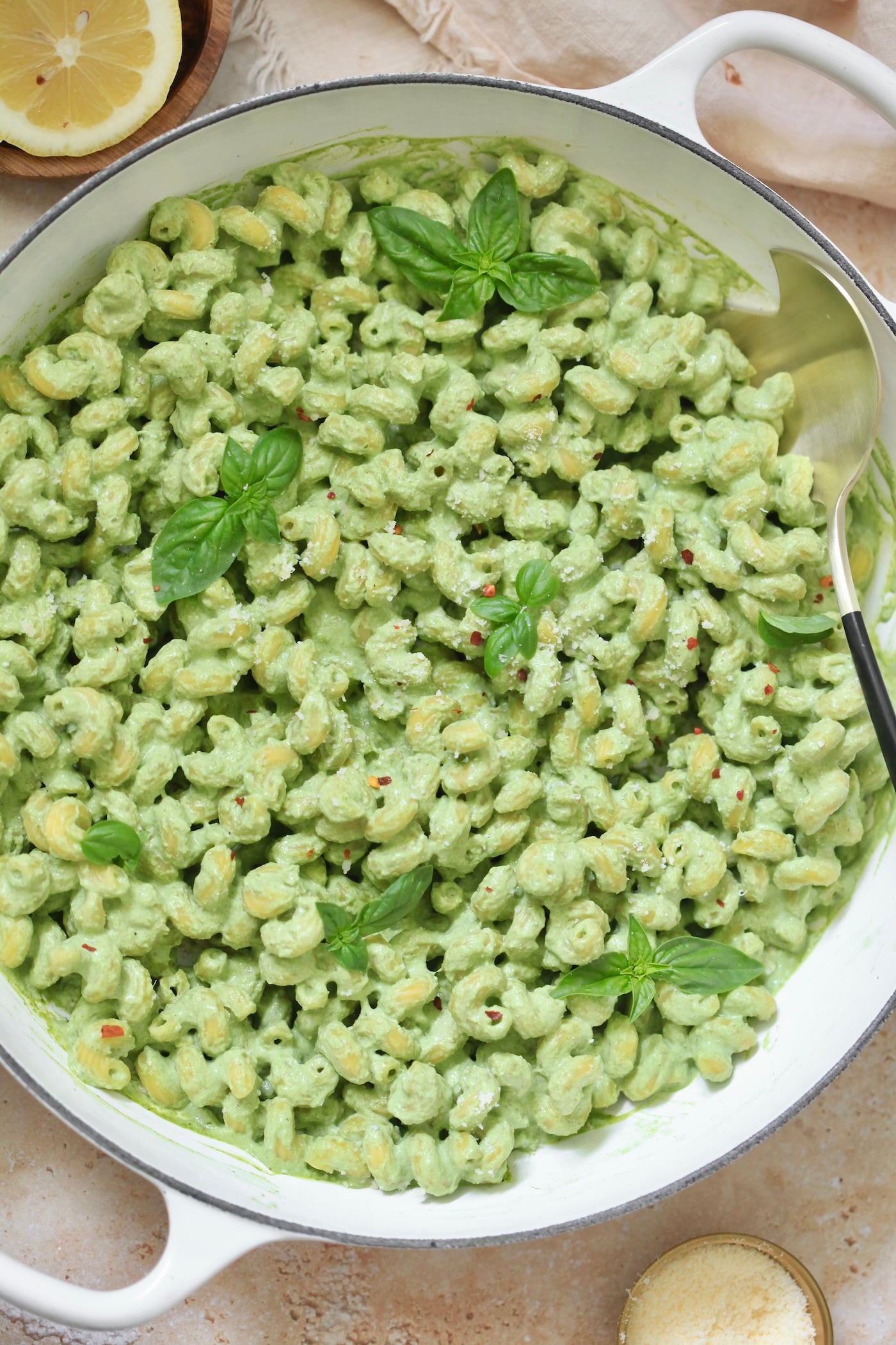white skillet with green pasta.