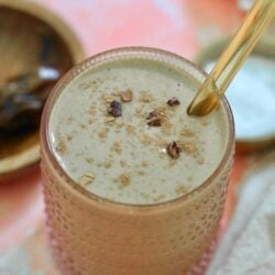 brown smoothie in glass with gold straw.