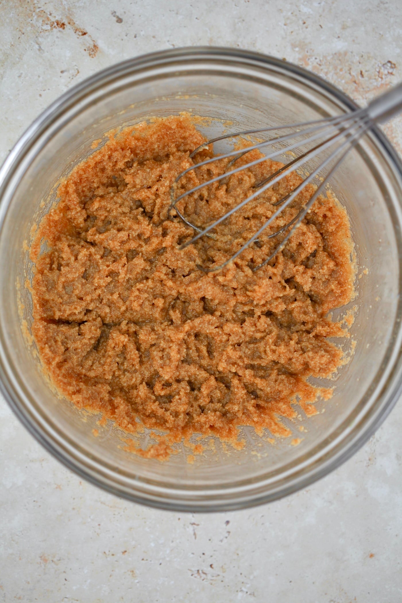 wet brown cookie dough in bowl with whisk.