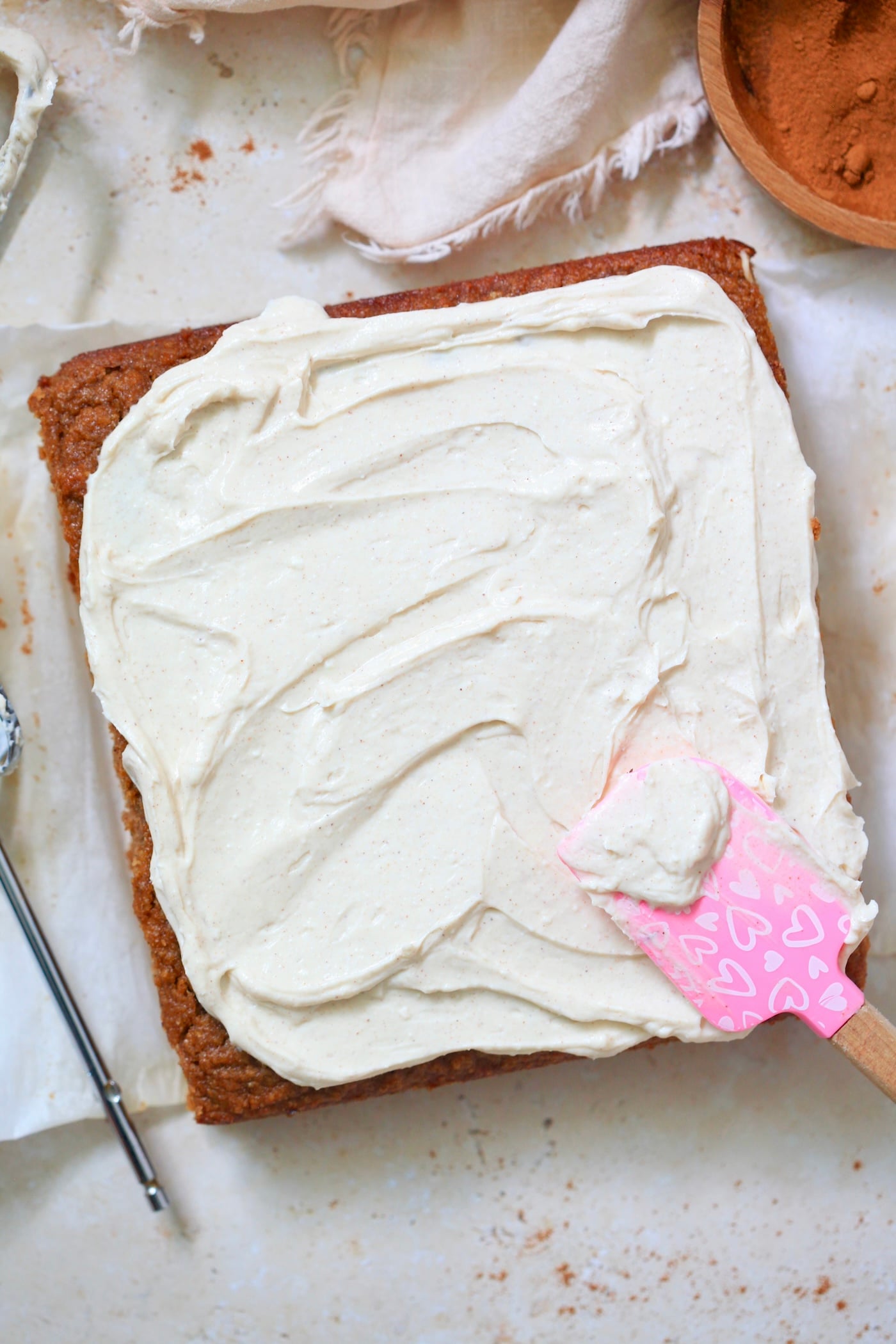 entire cake with spatula frosting it in white frosting.