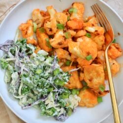 orange veggies with green slaw in white bowl.