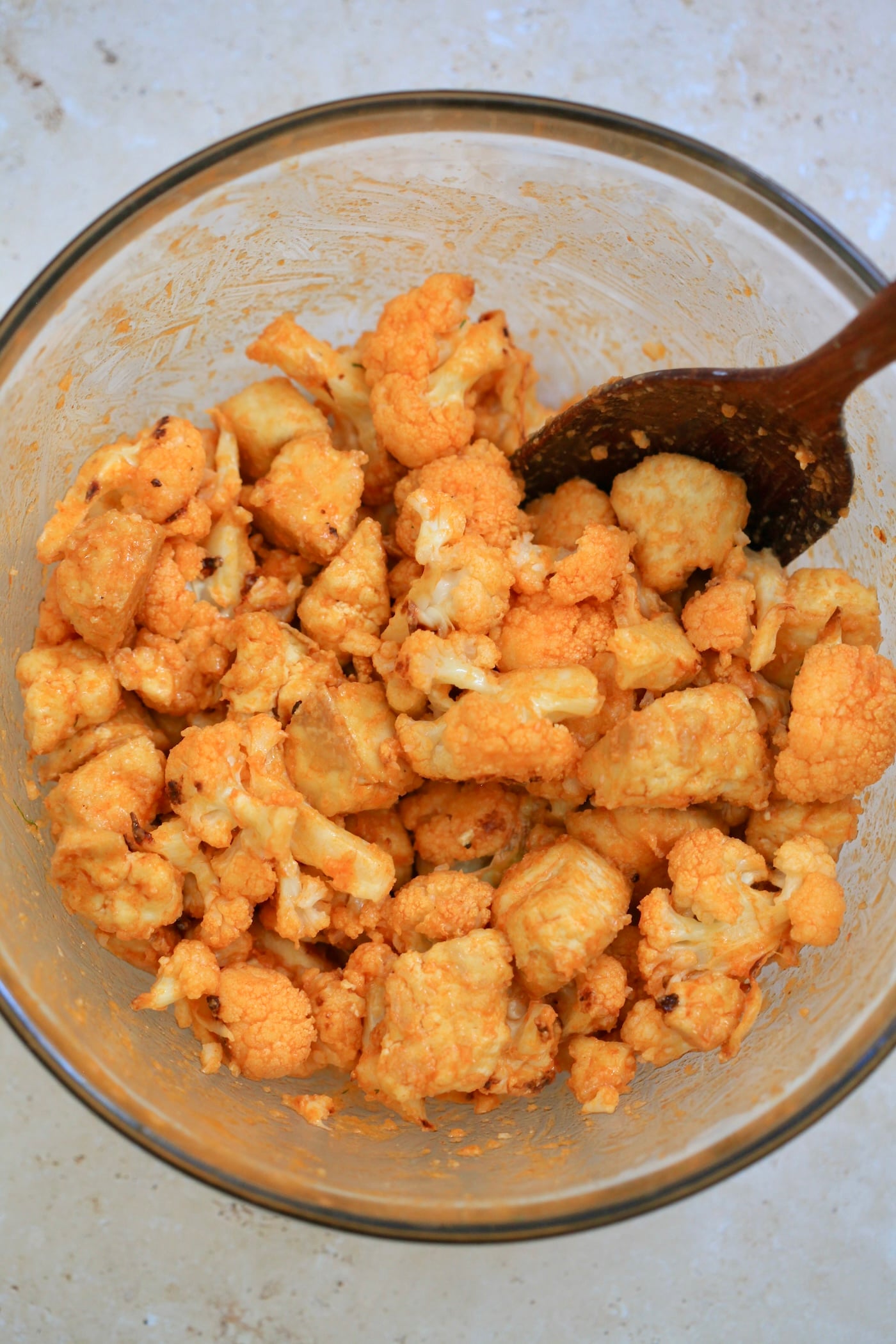 orange tofu and cauliflower in mixing bowl