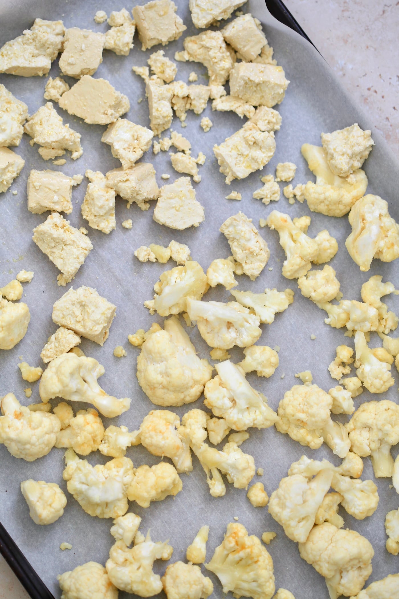 raw cauliflower and tofu on lined baking sheet