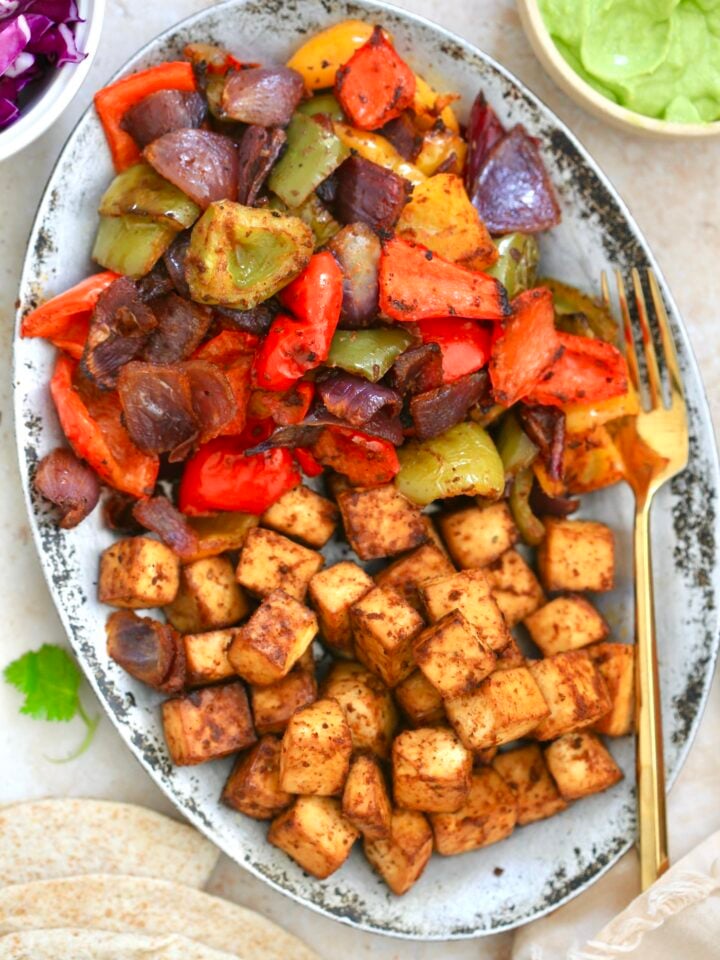 silver platter with brown cubes and cooked peppers.