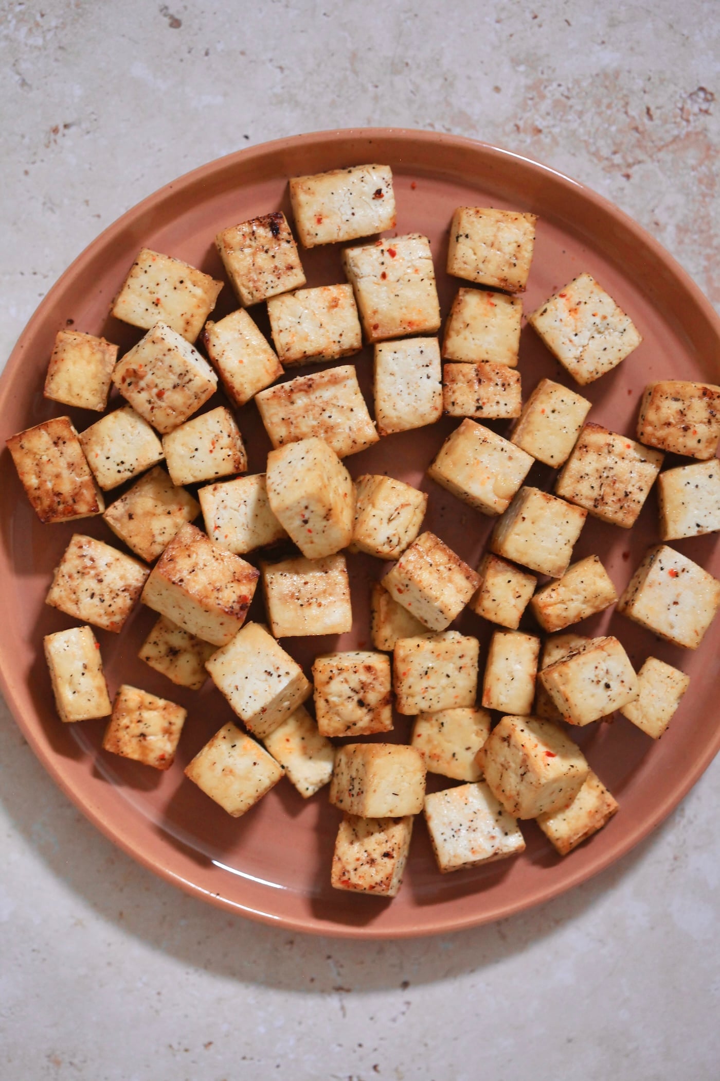 brown plate with cooked cubed tofu.