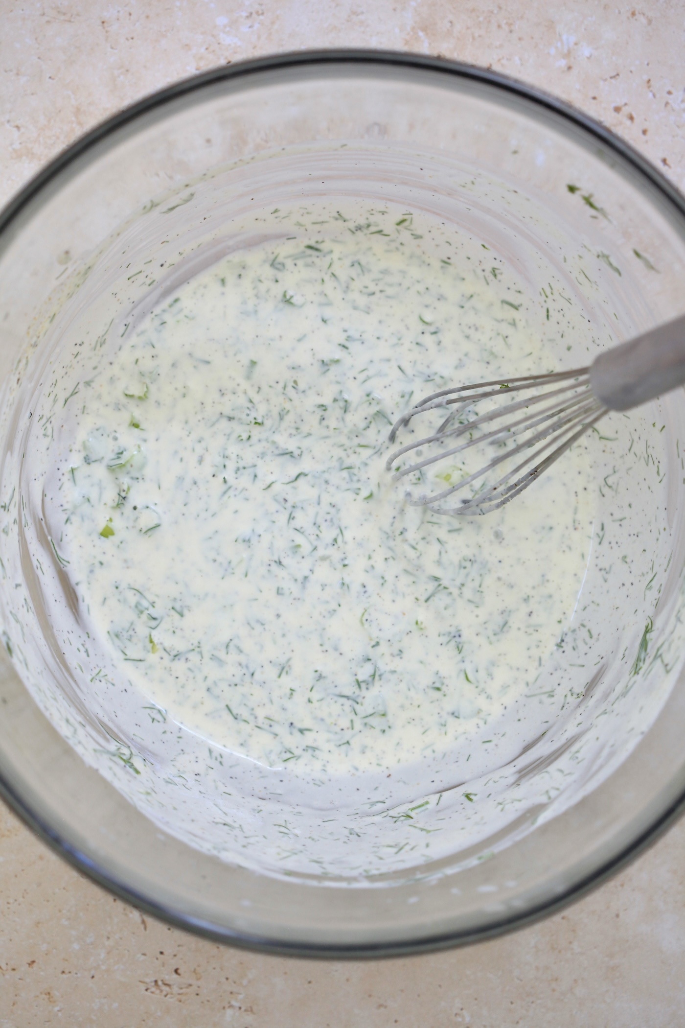 mixed herby yogurt dressing in bowl with whisk.