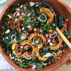 wooden bowl with kale salad and squash and serving spoon