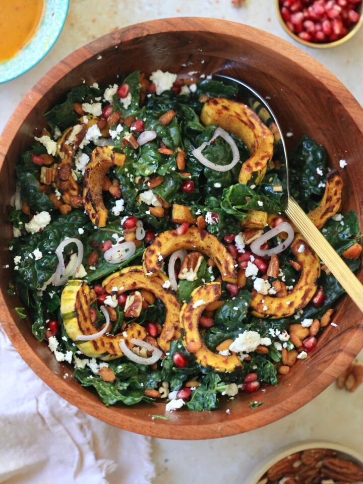 wooden bowl with kale salad and squash and serving spoon