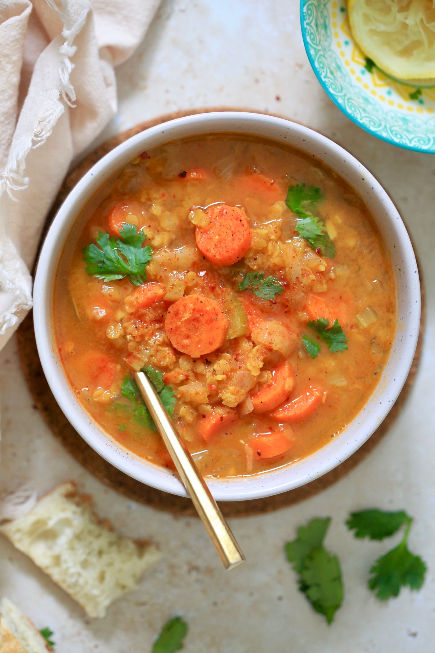 bowl of lentil soup with carrots and gold spoon.