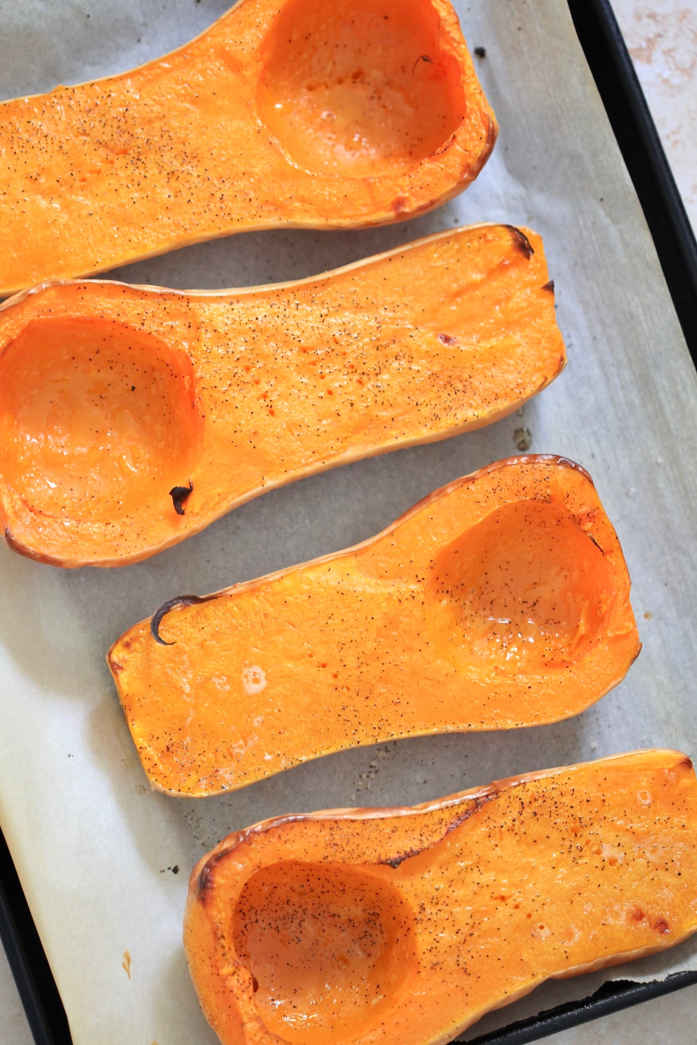 four roasted butternut squash halves on baking sheet.