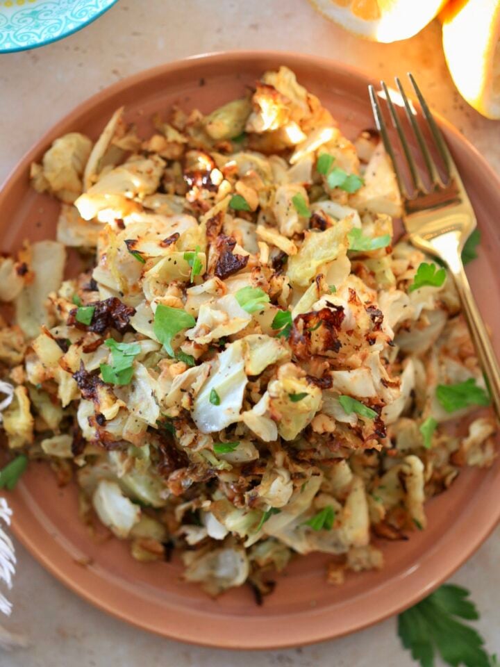 roasted green cabbage on brown plate with green fork