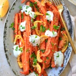 silver platter with roasted carrots and dots of yogurt