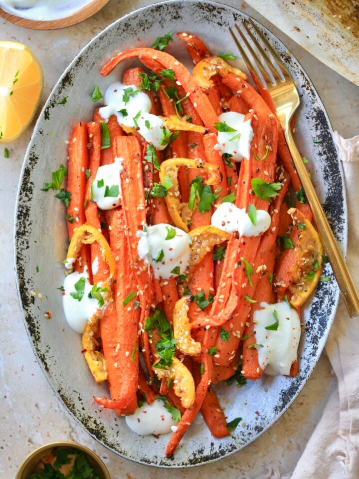 silver platter with roasted carrots and dots of yogurt