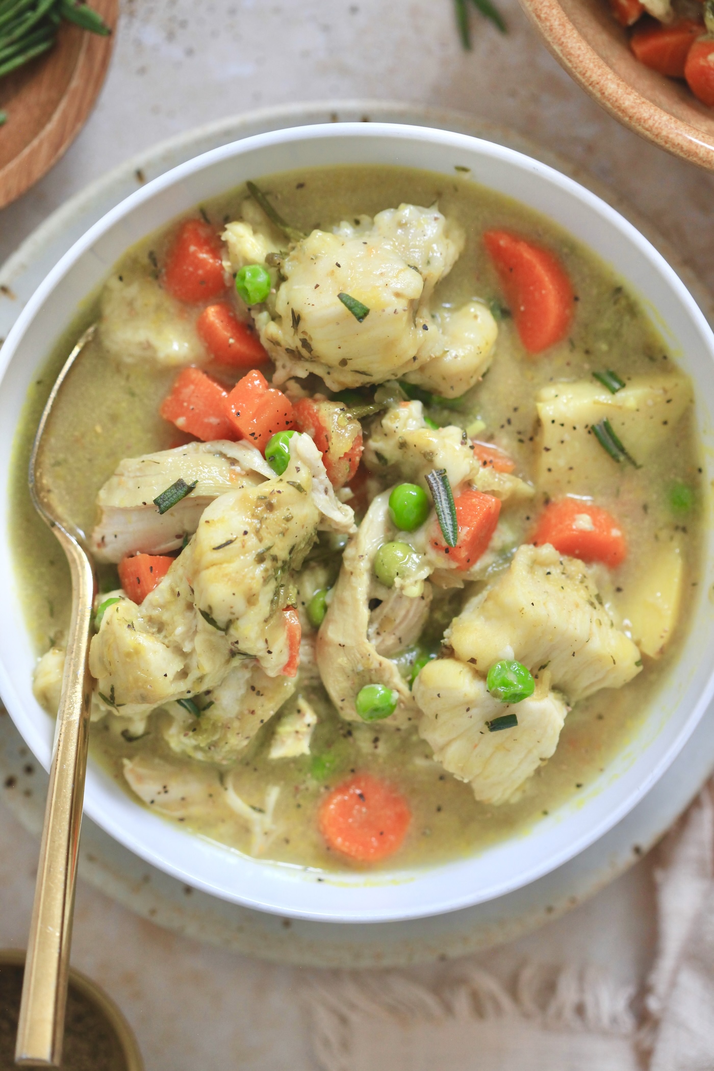 up closer bowl of veggie chicken soup with gold fork.