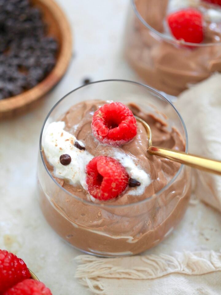 glass filled with chocolate pudding, whipped cream, and raspberries