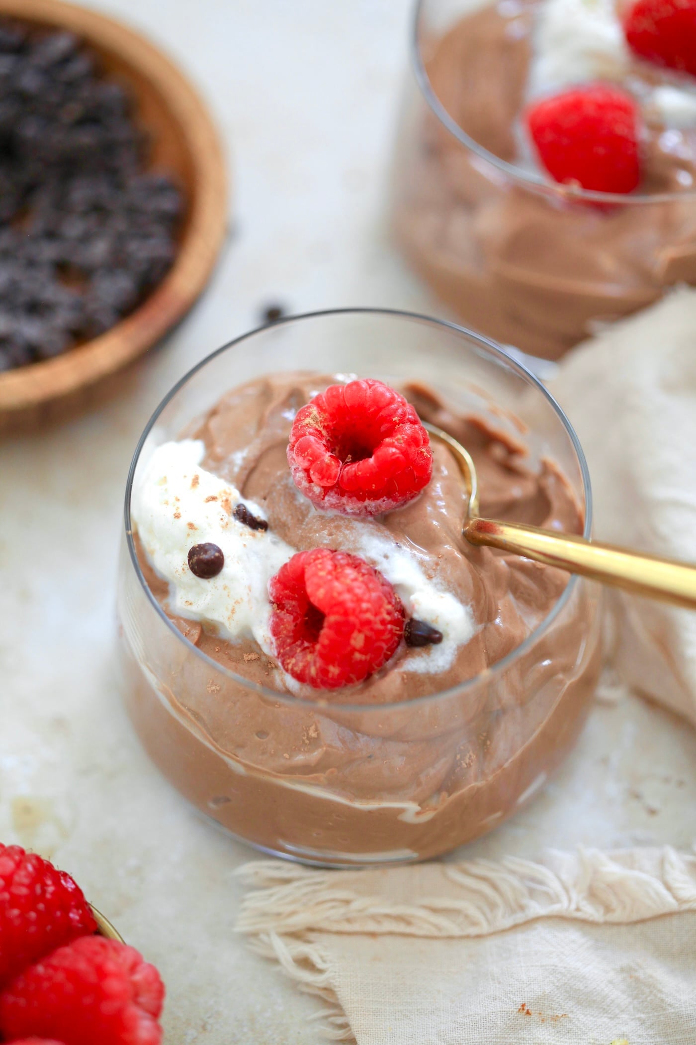 glass filled with chocolate pudding, whipped cream, and raspberries