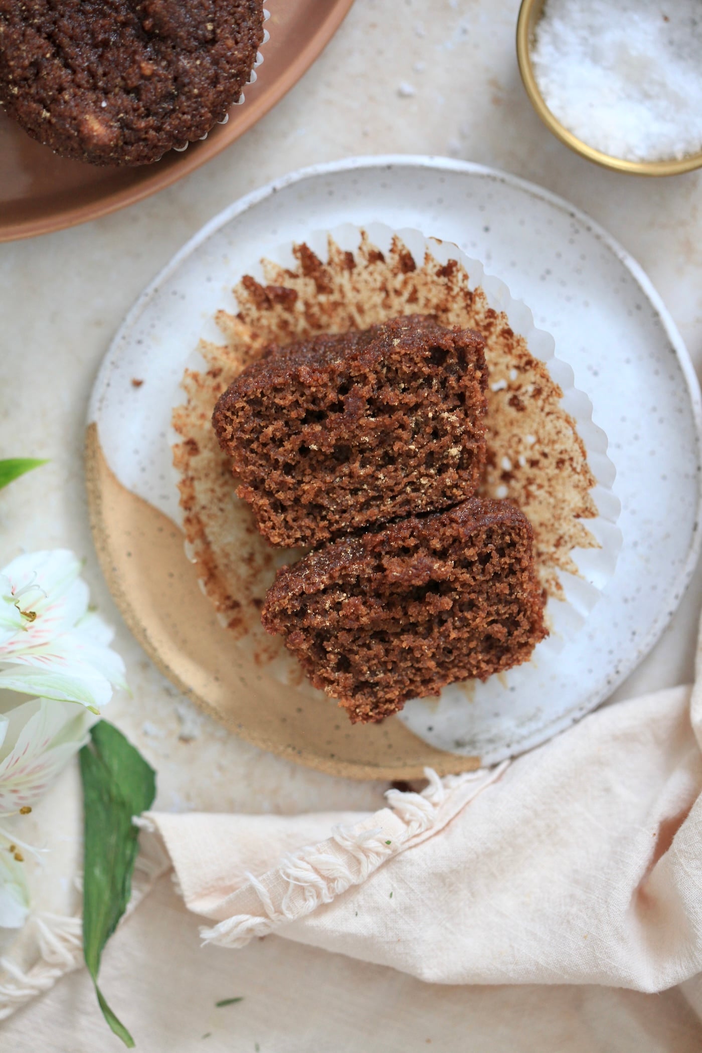 halved brown muffin in liner on plate.