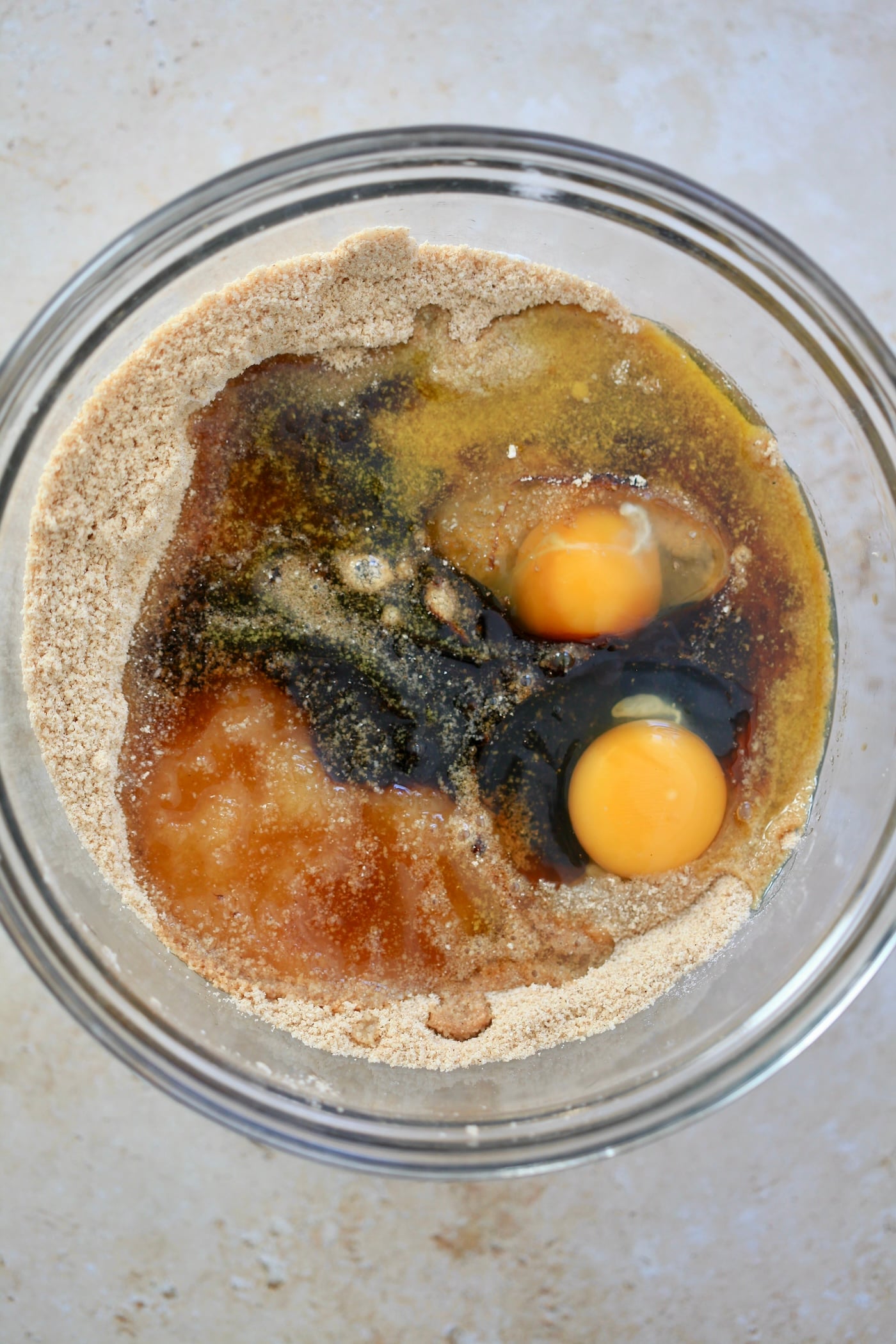 eggs and molasses over flour in glass mixing bowl.