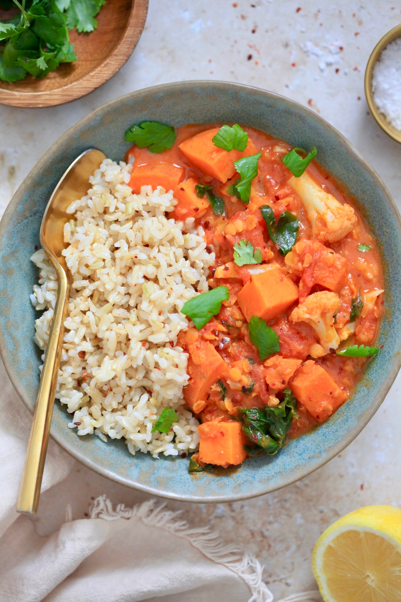 orange veggie mixture with brown rice in bowl with spoon.