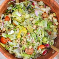 wooden bowl of colorful salad with serving spoons.