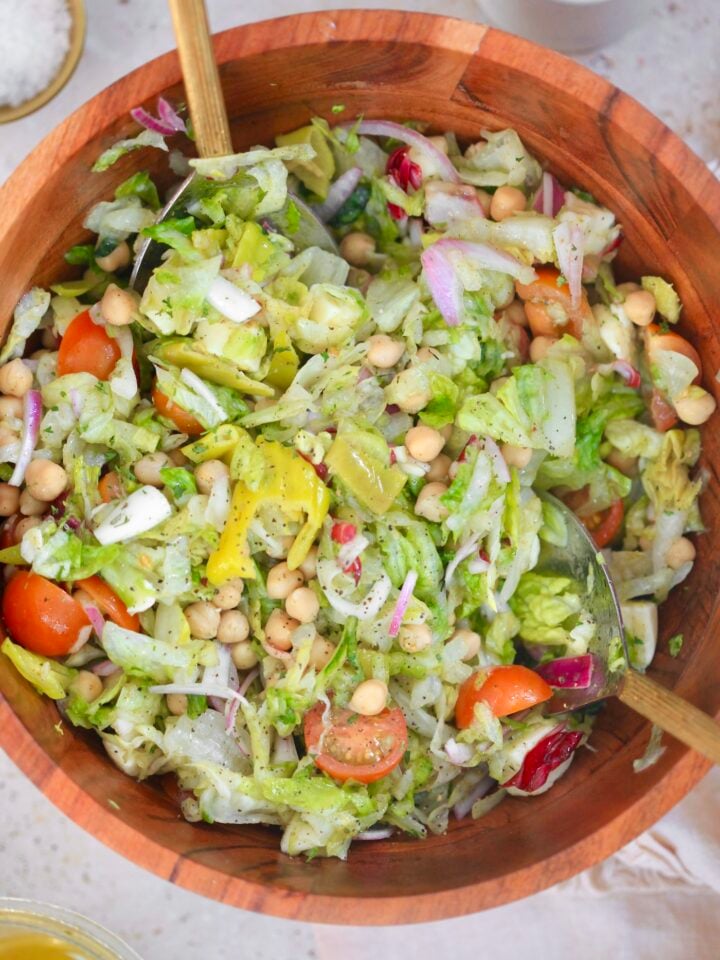 wooden bowl of colorful salad with serving spoons.