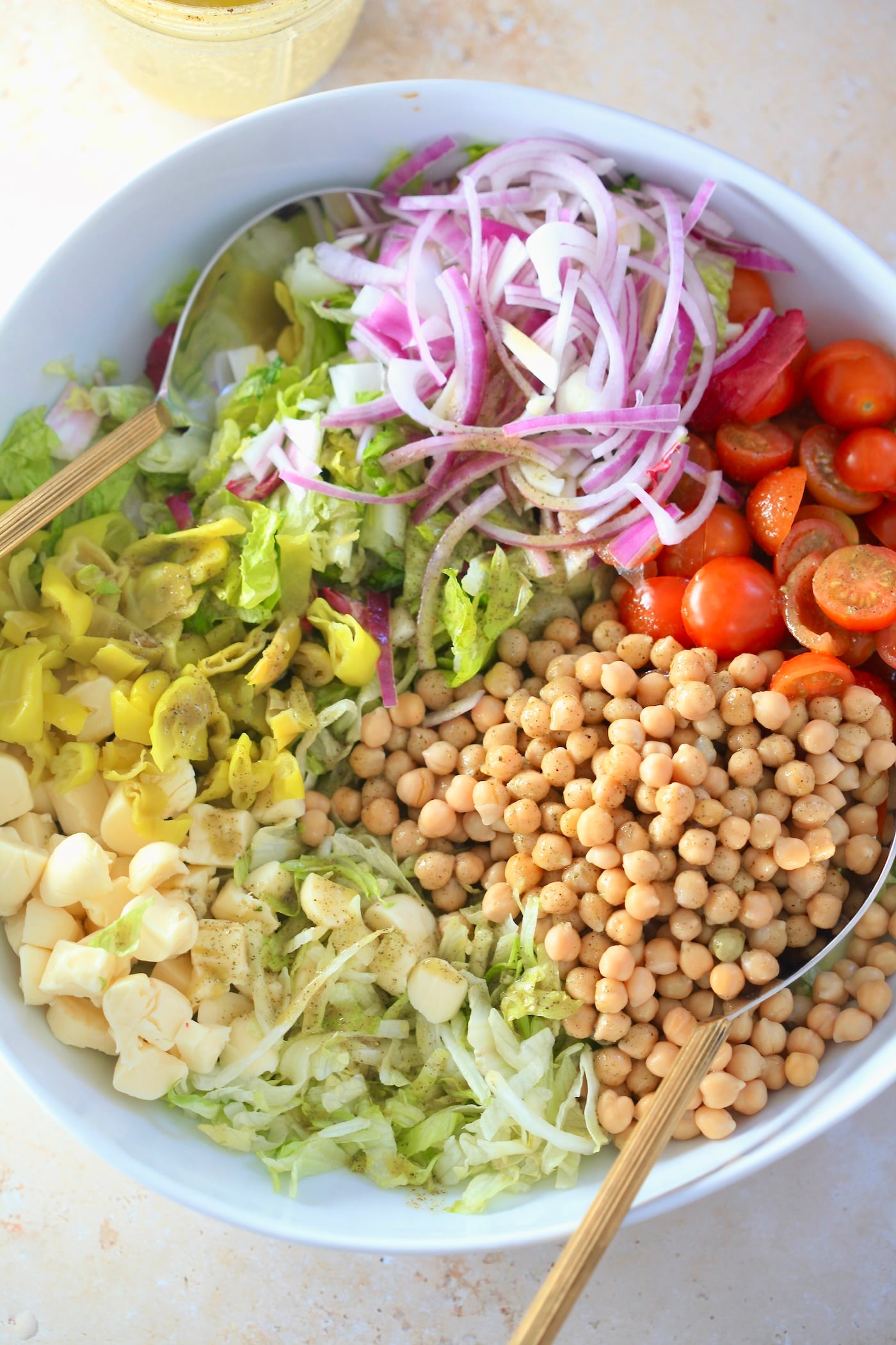 chickpeas, lettuce, cheese, tomatoes in mixing bowl.
