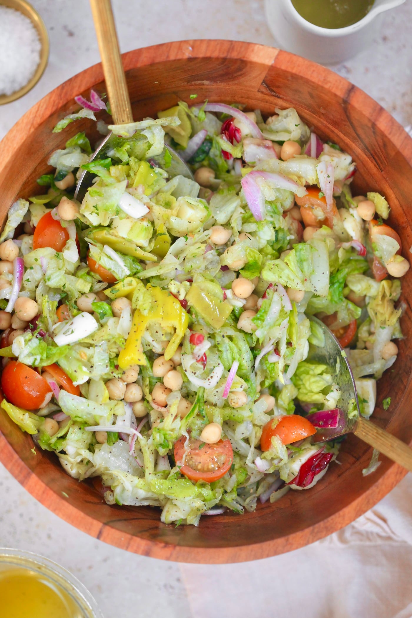 wooden bowl of colorful salad with serving spoons.