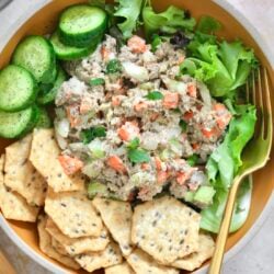 bowl with sardine salad and crackers and cucumbers.