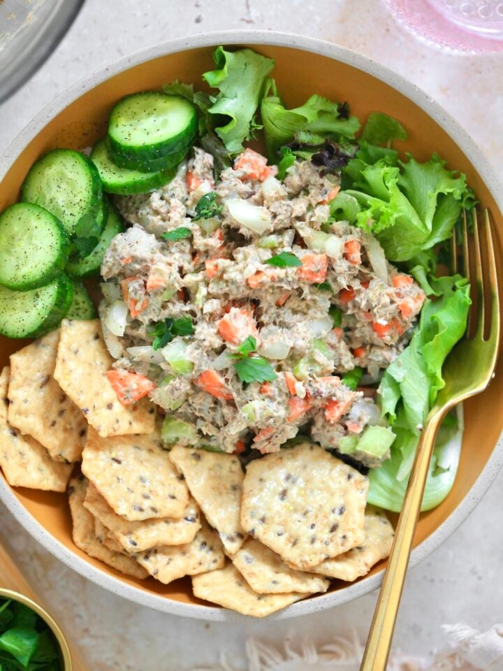 bowl with sardine salad and crackers and cucumbers.