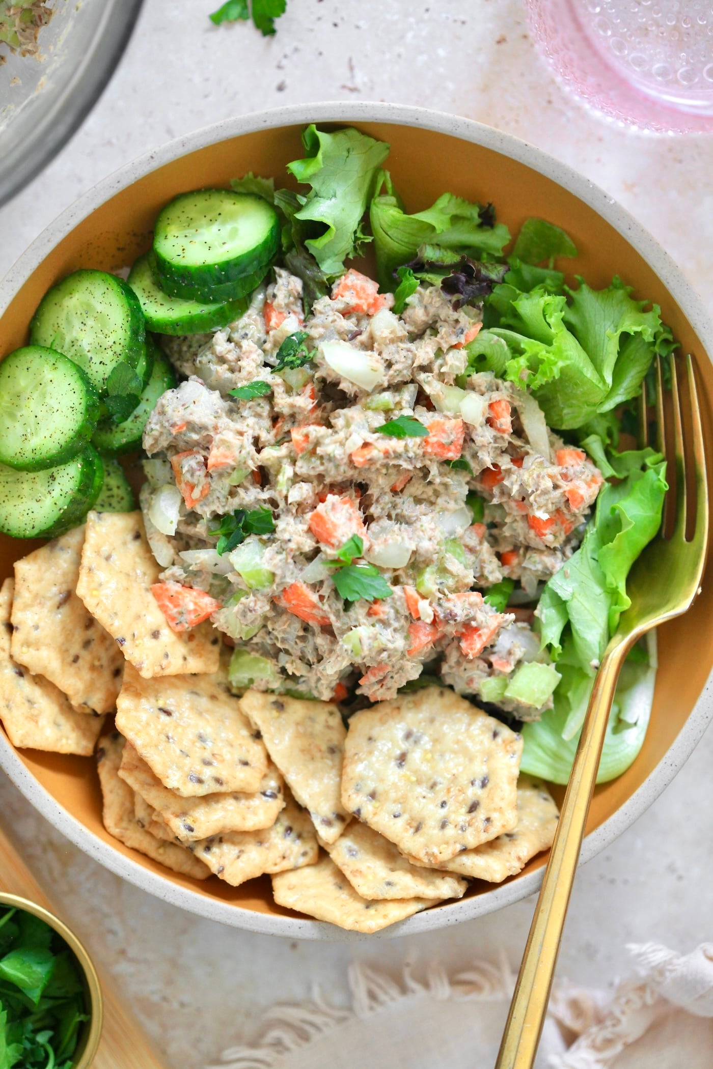 bowl with sardine salad and crackers and cucumbers.