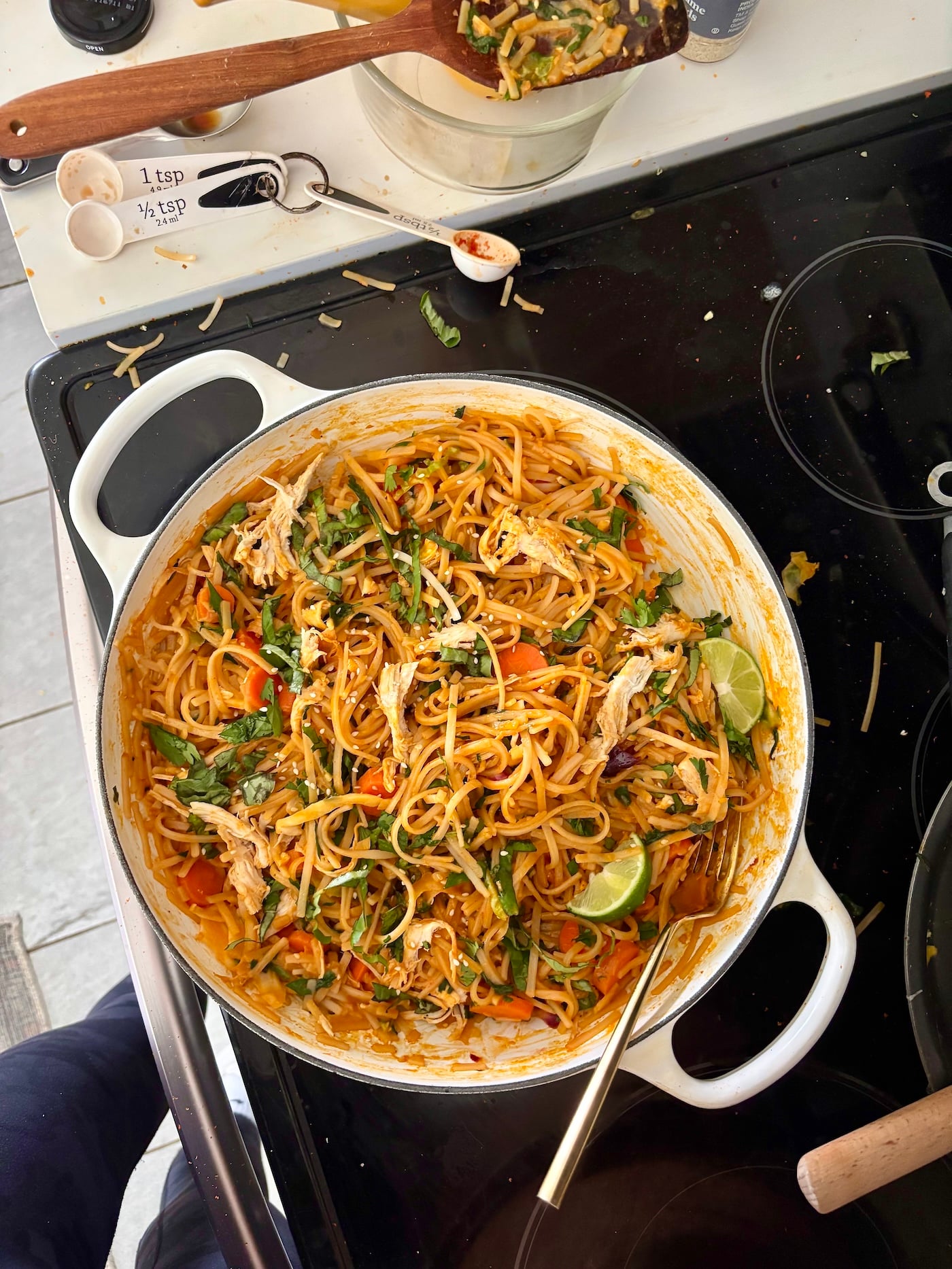 overhead view of white pan on black stove with noodles.