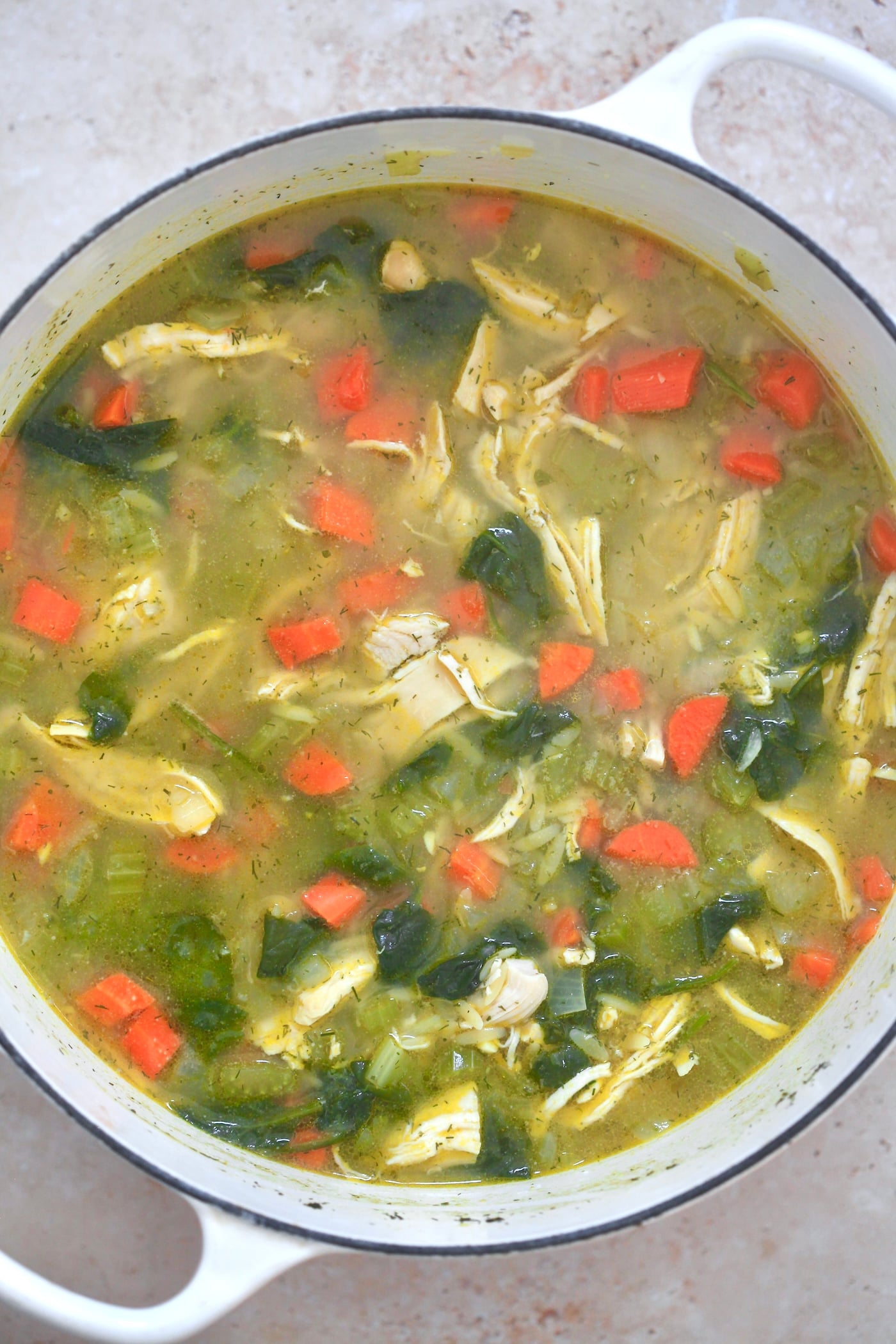 yellow soup in pot with veggies and chicken.